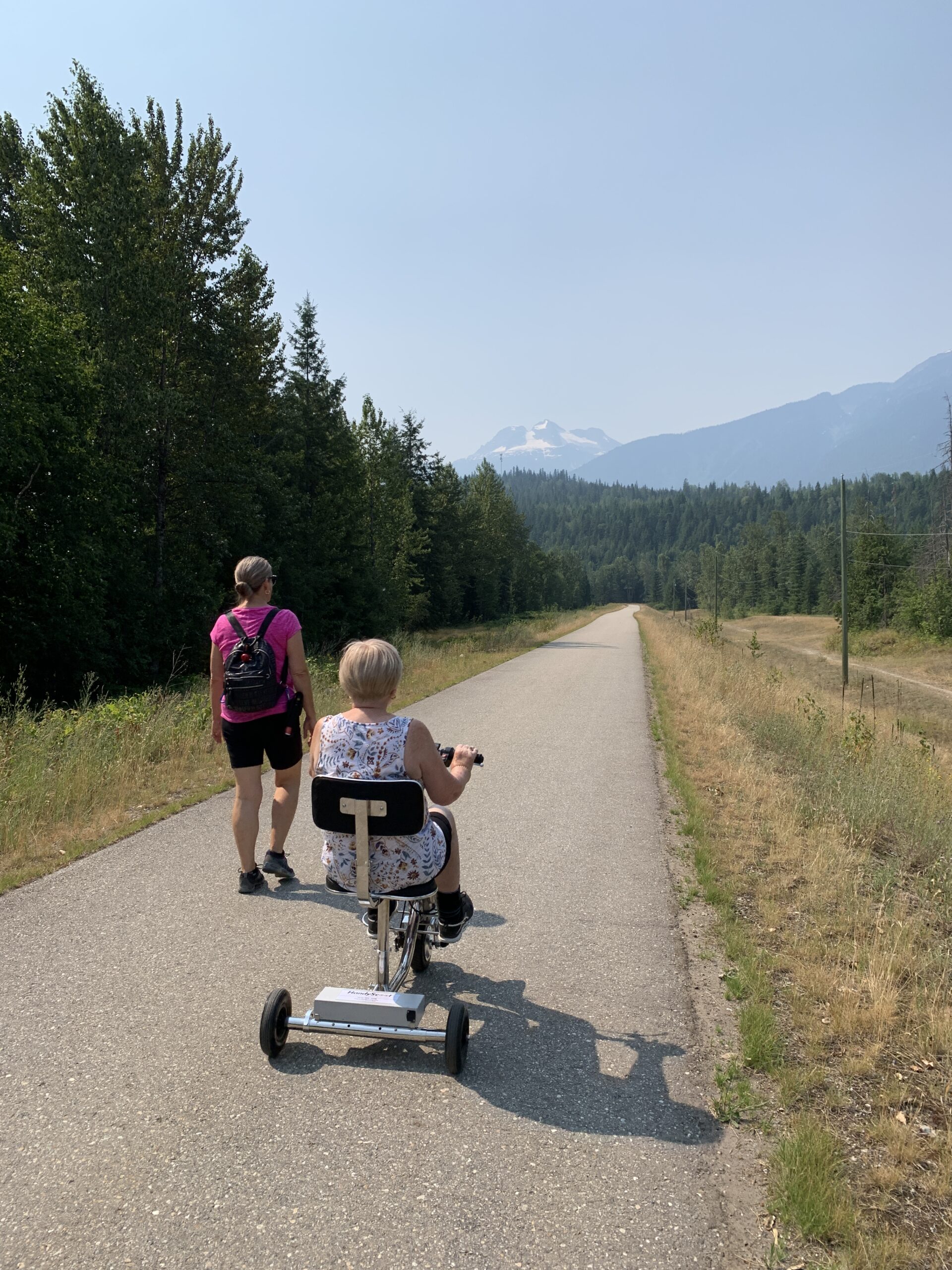 A woman riding a 3 wheel mobility scooter going for a ride with her daughter