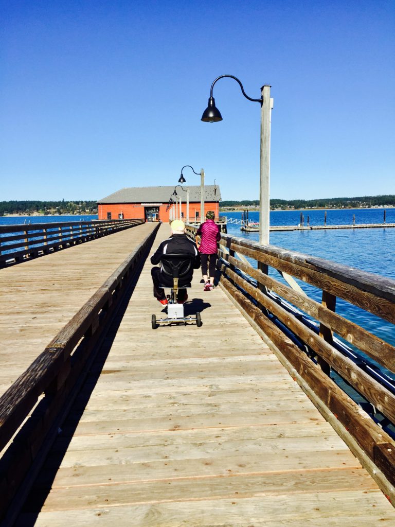 man riding his three wheel mobility scooter down a long pier